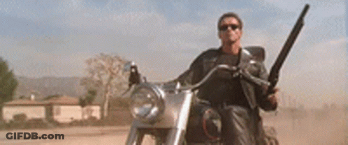 A Man Is Riding A Motorcycle Down A Dirt Road While Holding A Helmet . GIF