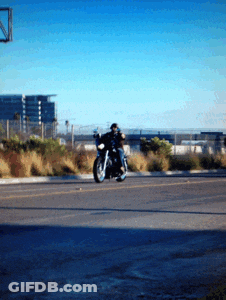 A Man Is Riding A Motorcycle Down A Road In A Parking Lot GIF