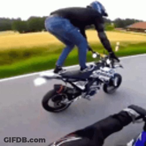 A Man Is Riding A Motorcycle Down A Road While Wearing A Helmet . GIF