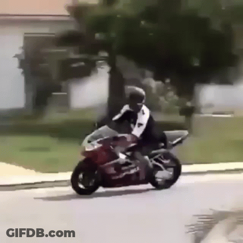 A Man Is Riding A Motorcycle Down A Street In Front Of A House . GIF