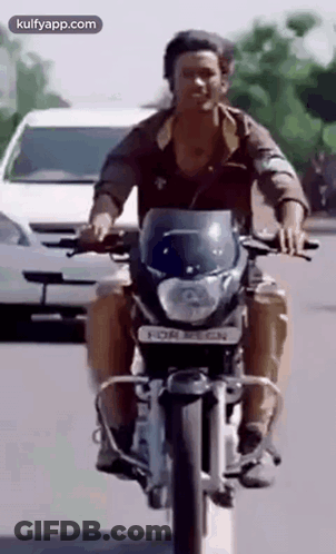 A Man Is Riding A Motorcycle Down A Street Next To A White Car . GIF