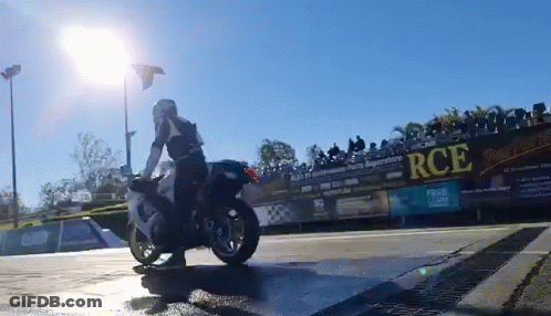 A Man Is Riding A Motorcycle In Front Of A Fence With Rce Written On It GIF
