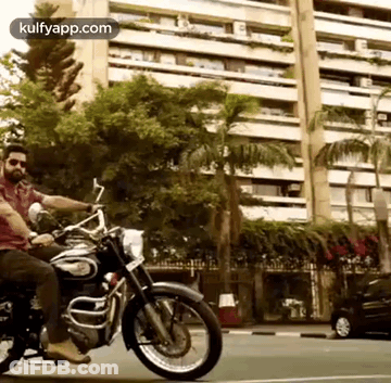 A Man Is Riding A Motorcycle On A City Street . GIF