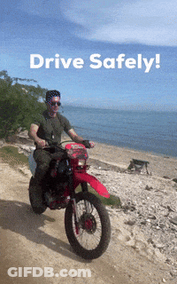 A Man Is Riding A Motorcycle On A Dirt Road With The Words Drive Safely Written Above Him GIF