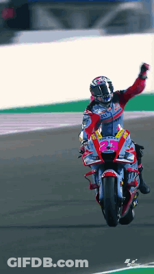 A Man Is Riding A Motorcycle On A Track With His Arm Up GIF