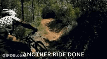 A Man Is Riding A Mountain Bike Down A Dirt Road . GIF