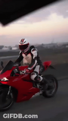 A Man Is Riding A Red Motorcycle With A Helmet That Has The Letter G On It GIF