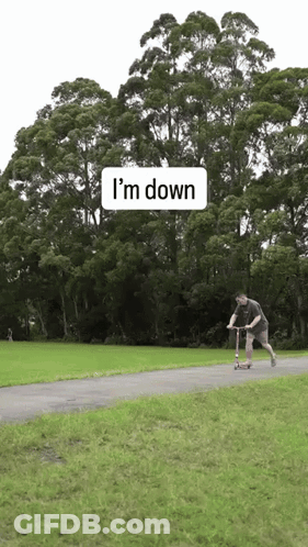 A Man Is Riding A Scooter Down A Path With Trees In The Background And A Sign That Says I 'M Down GIF