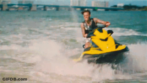 A Man Is Riding A Yellow Jet Ski On The Water GIF