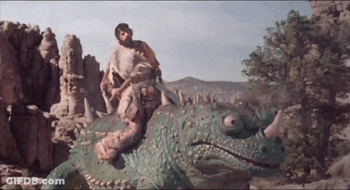 A Man Is Riding On The Back Of A Green Dinosaur With Horns GIF