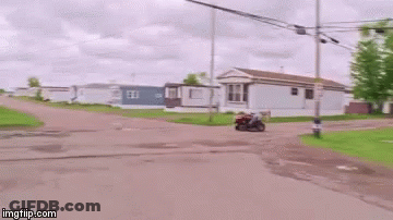 A Man Is Riding On The Back Of A Lawn Mower . GIF