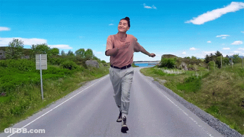 A Man Is Running Down A Road With A Sign That Says No Trucks GIF