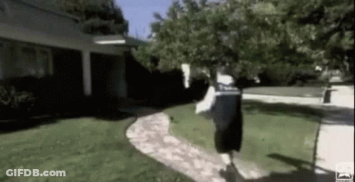 A Man Is Running Down A Sidewalk In A Yard . GIF