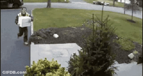 A Man Is Running Down The Street Carrying A Box In His Hand . GIF
