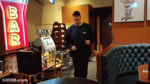 A Man Is Running In Front Of A Bar Sign GIF