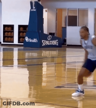 A Man Is Running On A Basketball Court With A Spalding Sign Behind Him GIF