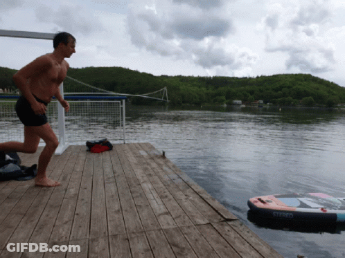 A Man Is Running On A Dock With A Stereo Inflatable In The Water GIF