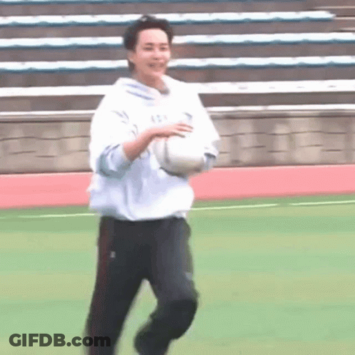 A Man Is Running On A Field With A Soccer Ball In His Hand . GIF