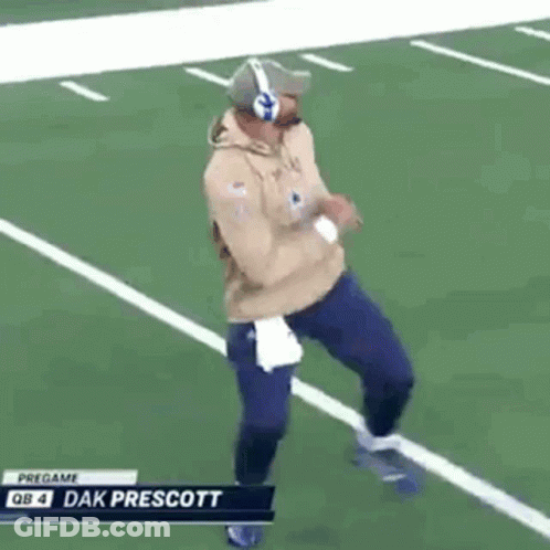 A Man Is Running On A Football Field Wearing Headphones And A Hat . GIF