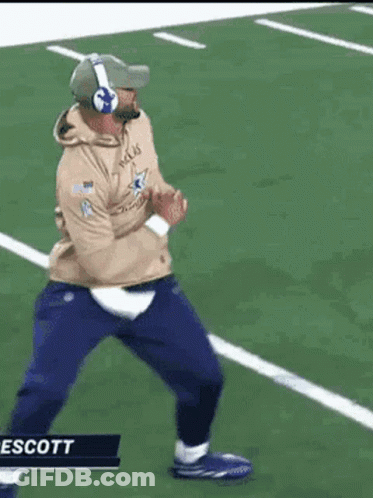 A Man Is Running On A Football Field Wearing Headphones . GIF