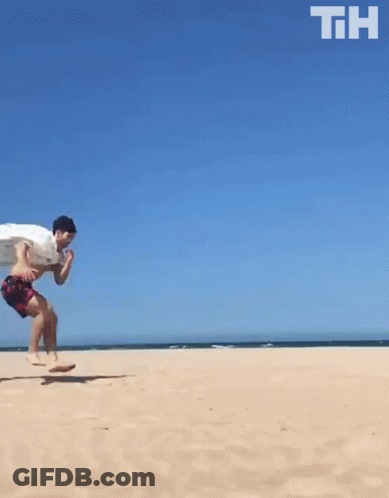 A Man Is Running On A Sandy Beach With The Letters Th Above Him GIF