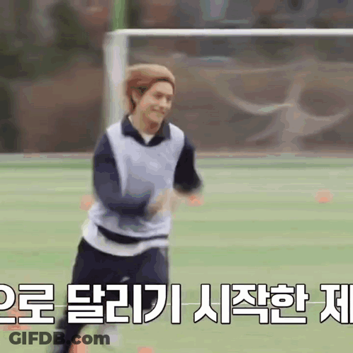 A Man Is Running On A Soccer Field With Chinese Writing Behind Him GIF