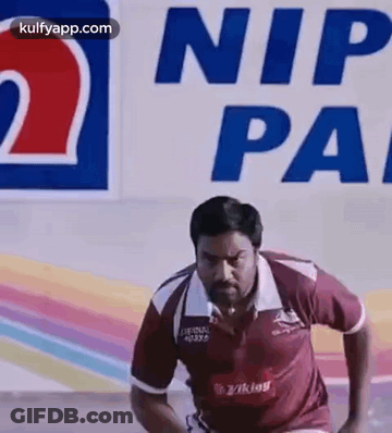 A Man Is Running On A Track In Front Of A Sign That Says Nip Pa . GIF