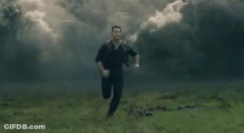 A Man Is Running Through A Field With Smoke Coming Out Of It . GIF