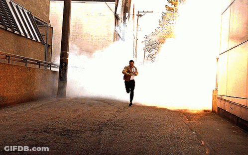 A Man Is Running Through A Smokey Alleyway GIF