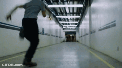A Man Is Running Through A Tunnel With A Yellow Line On The Floor GIF