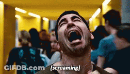 A Man Is Screaming In A Hallway With His Mouth Open . GIF