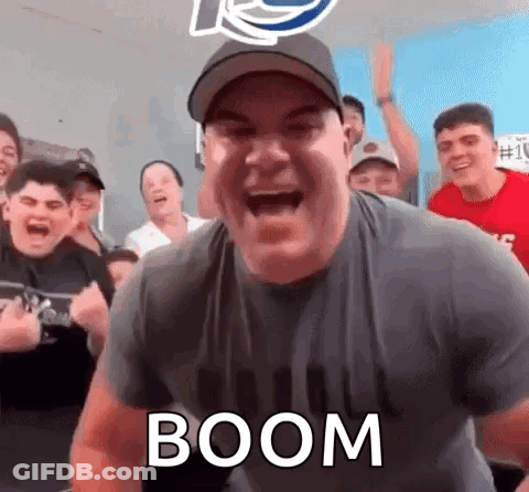 A Man Is Screaming In Front Of A Crowd Of People While Wearing A Hat And A Shirt That Says Boom . GIF