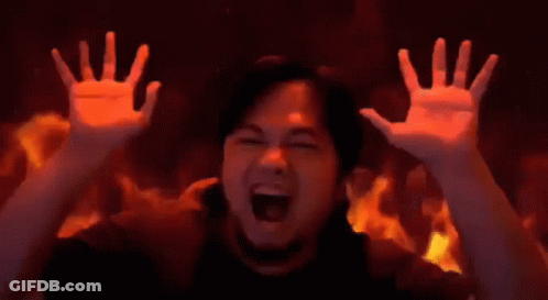 A Man Is Screaming In Front Of A Wall Of Fire . GIF