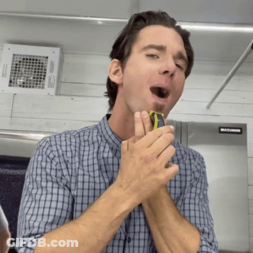 A Man Is Shaving His Face In Front Of A Maximum Fridge GIF