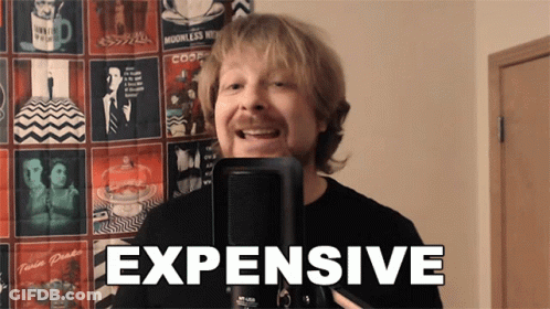 A Man Is Singing Into A Microphone And The Word Expensive Is On The Screen Behind Him GIF
