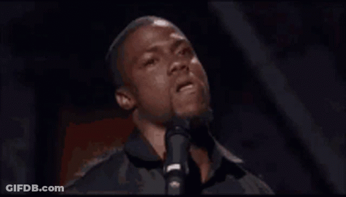 A Man Is Singing Into A Microphone In A Dark Room GIF