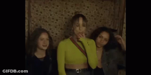 A Man Is Singing Into A Microphone In A Dark Room With Smoke Coming Out Of It . GIF