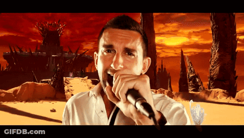 A Man Is Singing Into A Microphone In Front Of A Castle GIF