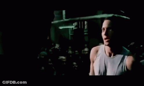 A Man Is Singing Into A Microphone In Front Of A Crowd At A Concert . GIF