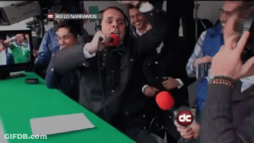 A Man Is Singing Into A Microphone In Front Of A Green Screen That Says Dc GIF