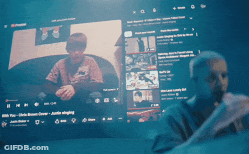 A Man Is Singing Into A Microphone In Front Of A Youtube Screen GIF