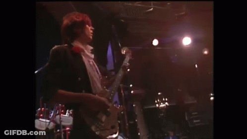 A Man Is Singing Into A Microphone On A Stage In Front Of A Crowd Of People . GIF