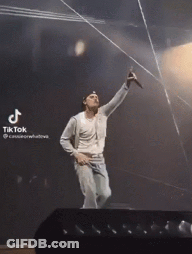 A Man Is Singing Into A Microphone On A Stage With A Tiktok Watermark GIF