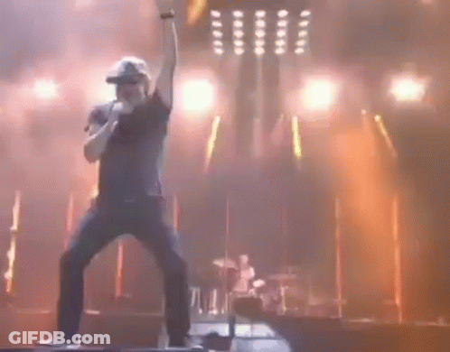 A Man Is Singing Into A Microphone On Stage GIF