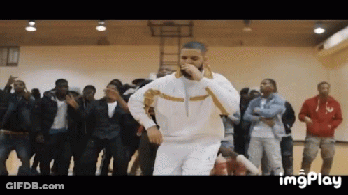 A Man Is Singing Into A Microphone While Dancing In Front Of A Crowd . GIF