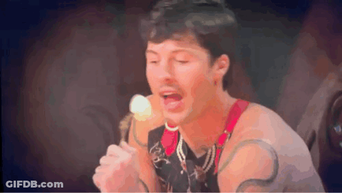 A Man Is Singing Into A Microphone While Holding An Ice Cream Cone .. GIF