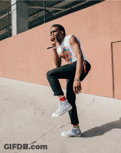 A Man Is Singing Into A Microphone While Kneeling Down GIF