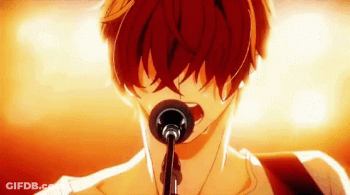 A Man Is Singing Into A Microphone While Playing A Guitar . GIF