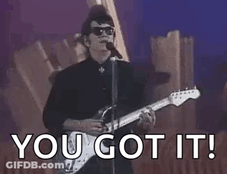 A Man Is Singing Into A Microphone While Playing A Guitar And Sunglasses . GIF