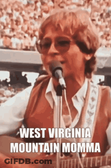 A Man Is Singing Into A Microphone While Playing A Guitar And Wearing Sunglasses . GIF